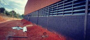 venezianas A imagem retrata uma Veneziana Industrial Solution com Pintura Eletrostática preto fosco instalada na fachada de um galpão industrial. A finalidade dessa instalação é proporcionar funcionalidade, estética e eficiência ao ambiente industrial.A Veneziana Industrial Solution é um elemento de ventilação e iluminação que permite o controle adequado do fluxo de ar e luz natural dentro do galpão. Com suas lâminas ajustáveis, é possível regular a ventilação de acordo com as necessidades do espaço, promovendo a circulação do ar e contribuindo para o conforto térmico dos funcionários e para a qualidade do ambiente de trabalho. Além disso, a pintura eletrostática preto fosco confere à veneziana um aspecto estético elegante e sofisticado, agregando valor visual ao galpão industrial. Essa escolha de cor também pode ter a finalidade de promover um melhor aproveitamento de luz natural, ao absorver menos calor e evitar o ofuscamento excessivo. Ao instalar a Veneziana Industrial Solution com Pintura Eletrostática no galpão, busca-se, portanto, uma solução que alia aspectos funcionais, como ventilação e iluminação, com uma estética moderna e elegante. Essa combinação contribui para a otimização do espaço industrial, proporcionando um ambiente mais agradável, produtivo e visualmente atraente para os colaboradores e visitantes do galpão.