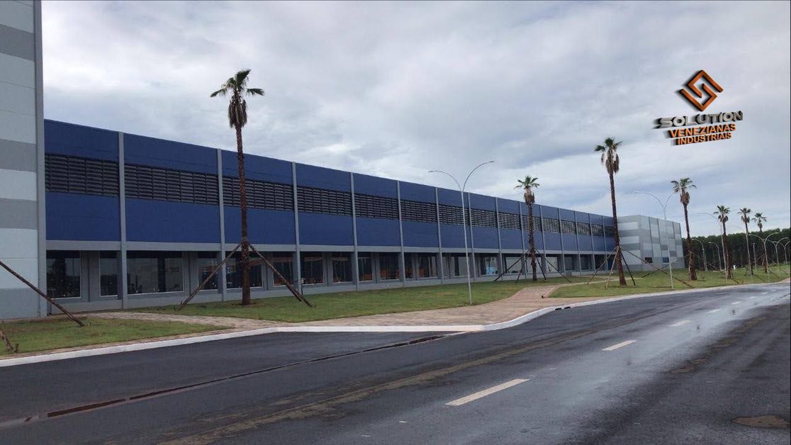 Solution Venezianas Industriais, A imagem mostra uma veneziana industrial de policarbonato instalada na fachada de um galpão industrial. Este modelo proporciona excelente ventilação e iluminação natural, melhorando as condições internas do ambiente de trabalho.