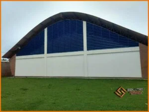 veneziana industrial Fachada em pintura eletrostática azul Del Rey aplicada em um ginásio poliesportivo tem como finalidade apresentar uma das possibilidades de aplicação do produto em um ambiente esportivo. A cor azul Del Rey utilizada na pintura eletrostática transmite elegância e modernidade, além de harmonizar com a maioria dos projetos arquitetônicos.A veneziana industrial Solution em pintura eletrostática azul Del Rey é ideal para o uso em ginásios poliesportivos, já que oferece uma ventilação natural adequada e uma iluminação natural que pode ser ajustada de acordo com as necessidades do espaço. A imagem exemplifica como o produto atua tanto em propriedades funcionais, contribuindo com a climatização e iluminação natural, como também em propriedades estéticas, trazendo harmonia e beleza ao ambiente do ginásio poliesportivo. Em resumo, a imagem mostra a veneziana industrial Solution em pintura eletrostática azul Del Rey como uma solução eficiente, prática e moderna para quem busca aliar conforto térmico, economia de energia elétrica e design sofisticado em ginásios e espaços poliesportivos.
