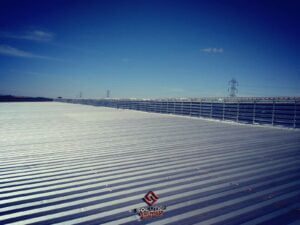 Lanternim Industrial Solution Lanternins A imagem mostra uma instalação de venezianas industriais em aço galvanizado Solution projetadas especificamente para a utilização em lanternins. As venezianas em aço galvanizado proporcionam uma solução robusta e durável para garantir a ventilação adequada e o controle de luminosidade em ambientes industriais. O aço galvanizado é conhecido por sua resistência à corrosão, garantindo a longevidade das venezianas mesmo em ambientes agressivos. Essas venezianas permitem a circulação eficiente de ar fresco, ajudando a regular a temperatura interna e melhorando a qualidade do ar. Além disso, a presença de luz natural contribui para a economia de energia elétrica e cria um ambiente mais confortável e produtivo para os trabalhadores. As venezianas industriais em aço galvanizado Solution para lanternins são projetadas para atender às necessidades específicas de ventilação e iluminação em telhados industriais, garantindo um ambiente seguro e adequado para diversas atividades industriais.
