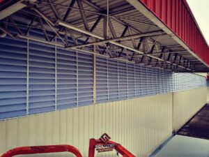 Venezianas Industriais Fachadas Solution A imagem da fachada com a veneziana industrial fabricada em policarbonato alveolar branco leitoso de 3mm translúcido tem como finalidade demonstrar a solução inovadora e versátil para controle de luz e ventilação. A transparência parcial do policarbonato permite a entrada de luz natural, criando um ambiente agradável, ao mesmo tempo que oferece privacidade. O material resistente, durável e de fácil manutenção proporciona uma fachada moderna e funcional, garantindo qualidade estética e desempenho excepcionais.