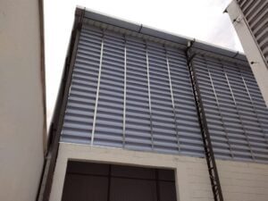 Veneziana Industrial Aleta em Fibra Aleta em Fibra de Vidro A imagem de "Venezianas Industriais com Aleta em Fibra de Vidro" tem como finalidade ilustrar visualmente o produto mencionado no texto, ou seja, as venezianas industriais equipadas com aletas feitas de fibra de vidro. A imagem provavelmente mostra as características e detalhes dessas aletas, como sua textura, cor e design, bem como sua integração nas venezianas industriais.Essa imagem serve para proporcionar aos leitores uma representação concreta do produto em questão, ajudando-os a entender melhor como as aletas em fibra de vidro são aplicadas nas venezianas industriais e como contribuem para o desempenho e eficiência desses sistemas de ventilação. Em resumo, a finalidade da imagem é complementar as informações do texto, tornando o conteúdo mais visual e informativo para os leitores.