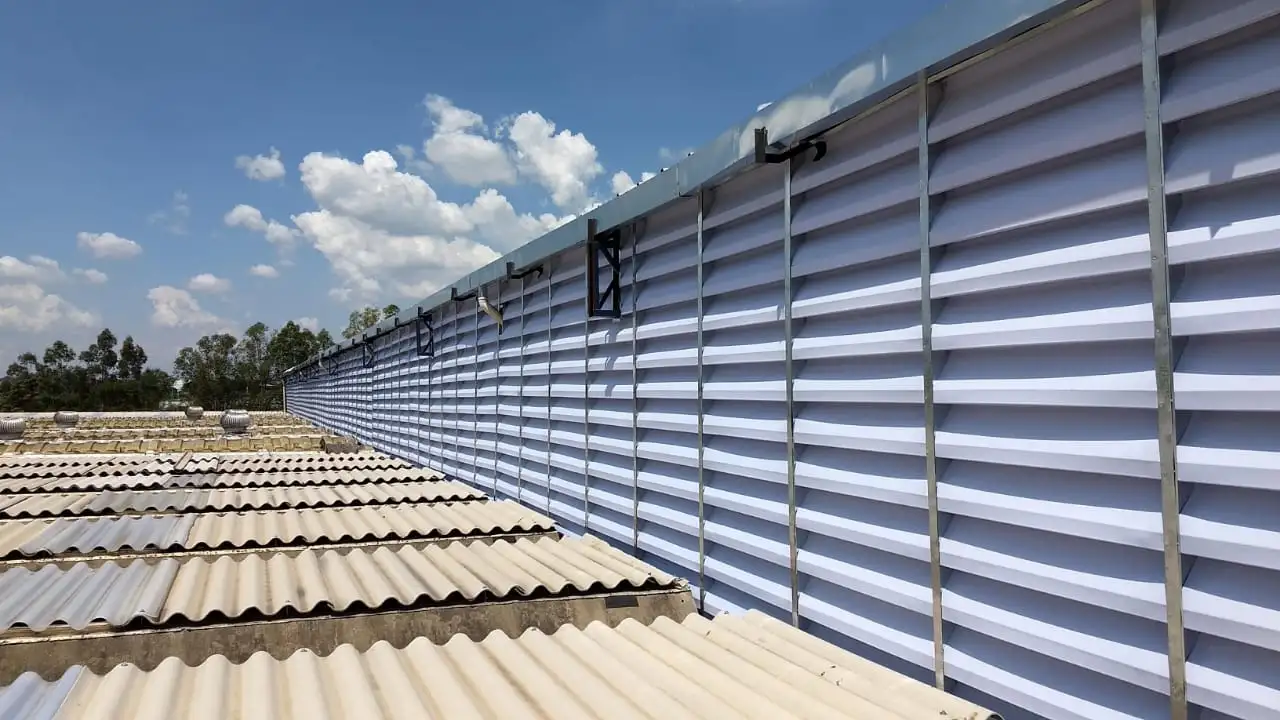 Lanternim O Que É? A imagem ilustra um lanternim, uma estrutura instalada no telhado de edificações industriais ou comerciais. Sua finalidade é proporcionar ventilação e iluminação natural para o interior do ambiente, ajudando a melhorar o conforto térmico e a qualidade do ar.
