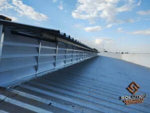 Lanternins Soluções Eficientes, A imagem destaca a eficiência dos lanternins da Solution, mostrando como eles são capazes de melhorar a ventilação e iluminação natural em ambientes industriais. O design e a instalação são pensados para otimizar o fluxo de ar e reduzir custos de energia, proporcionando um espaço mais saudável e produtivo.