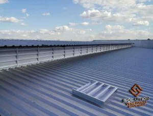 Lanternins Soluções Eficientes. Imagem ilustrando lanternins instalados no telhado de uma fábrica, demonstrando como esses equipamentos melhoram a ventilação e iluminação natural, reduzindo custos de energia e aumentando o conforto no ambiente de trabalho.