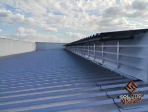 Lanternins Soluções Eficientes, A imagem destaca a funcionalidade dos lanternins da Solution, mostrando como eles proporcionam ventilação e iluminação natural eficiente em ambientes industriais, reduzindo custos com energia e melhorando o conforto no local de trabalho.